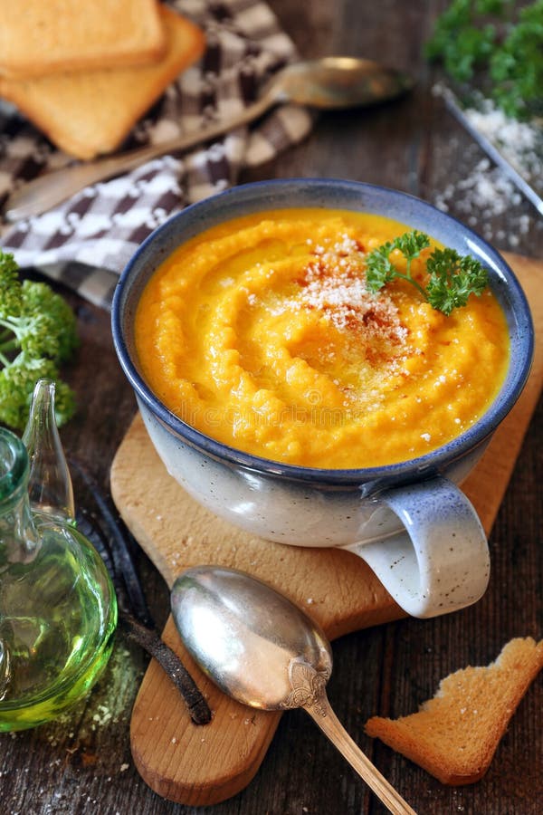 Vegetable carrot soup with parsley, grated cheese and toasted bread