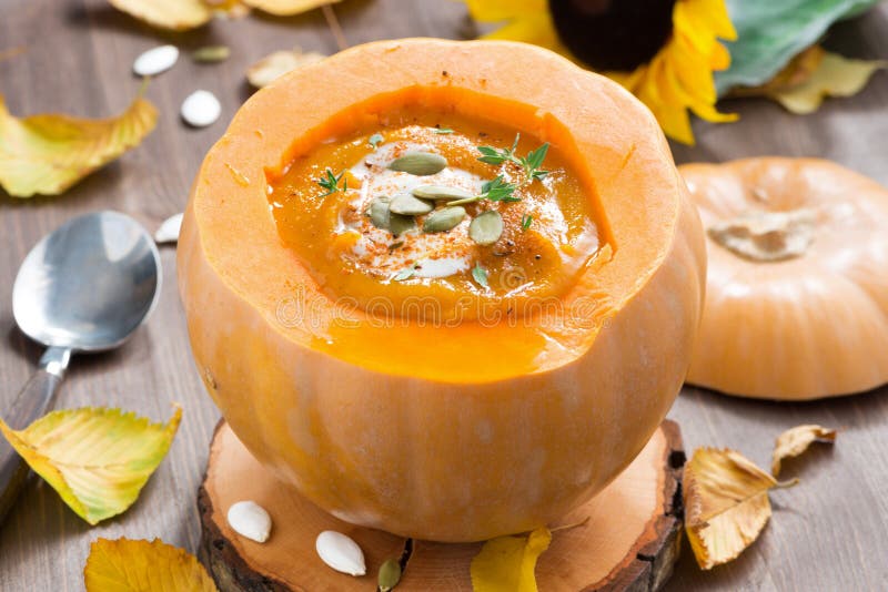 Vegetable cream soup in a pumpkin on a wooden table