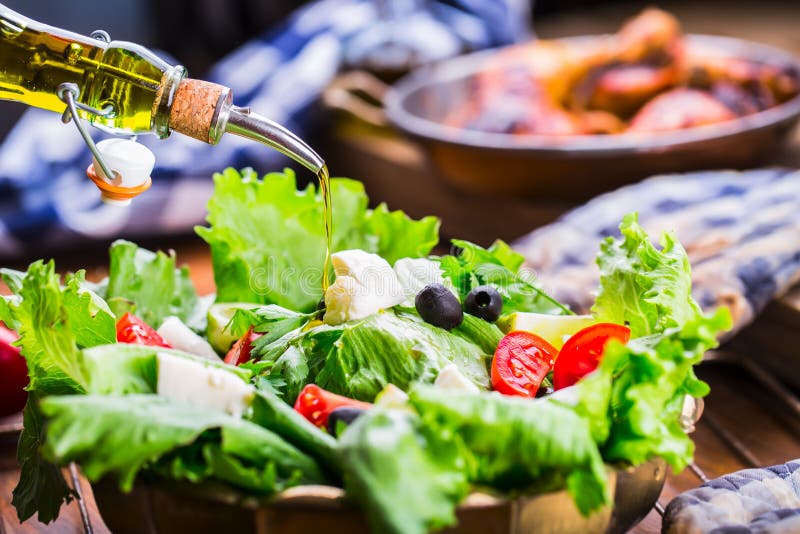 Vegetable lettuce salad. Olive oil pouring into bowl of salad. Italian Mediterranean or Greek cuisine. Vegetarian vegan food