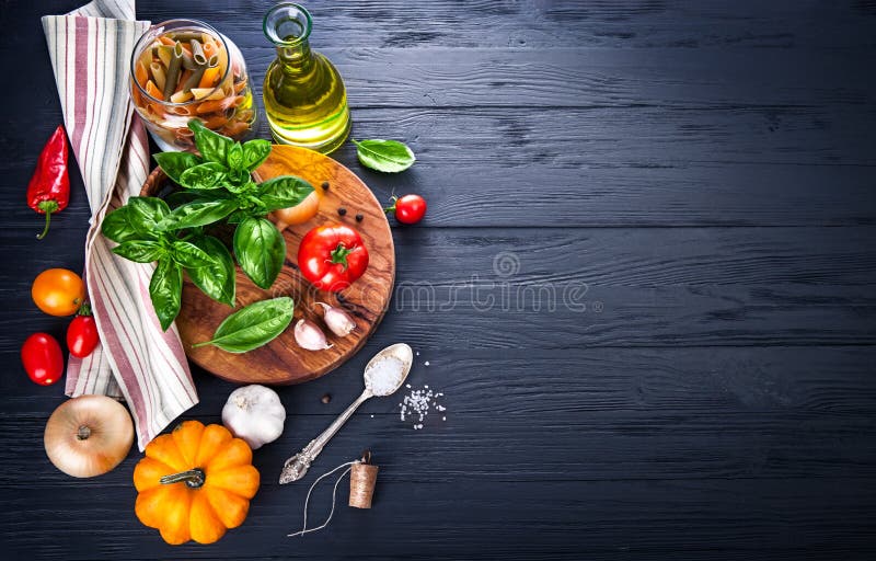 Le verdure e le spezie ingrediente per cucinare il cibo italiano su nero in legno vecchio consiglio in stile rustico.