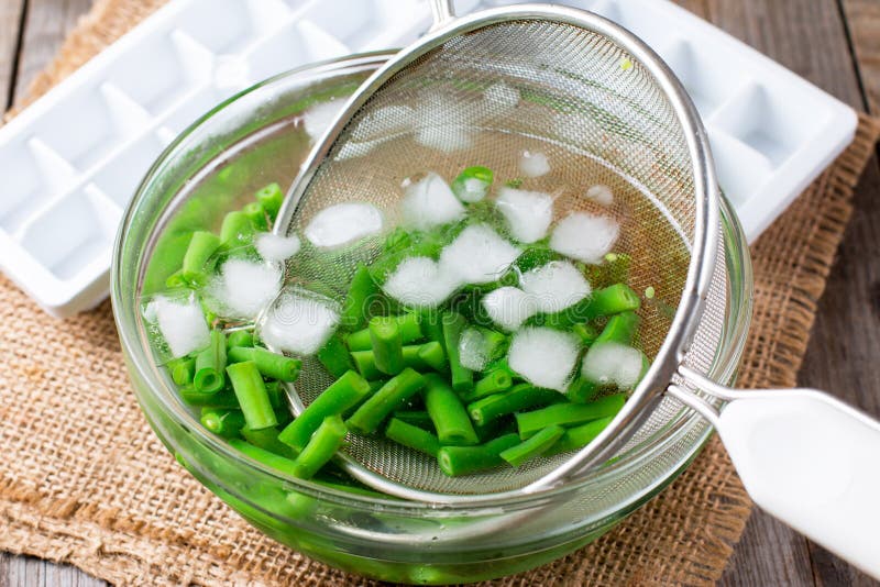 Vegetais fervidos, feijões verdes na água de gelo após o descascamento imagem de stock Vegetais fervidos, feijões verdes na água de gelo após o descascamento imagem de stock
