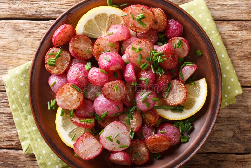 Vegetarian fried red radish with lemon and green onions close-up on a plate. horizontal top view