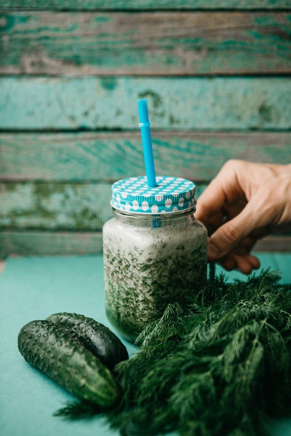 Vegetarian green mix of vegetable and fruit cocktail from cucumber and green parsley and dill. The person takes a jar. With a hand to drink stock photos Vegetarian green mix of vegetable and fruit cocktail from cucumber and green parsley and dill. The person takes a jar. With a hand to drink stock photos