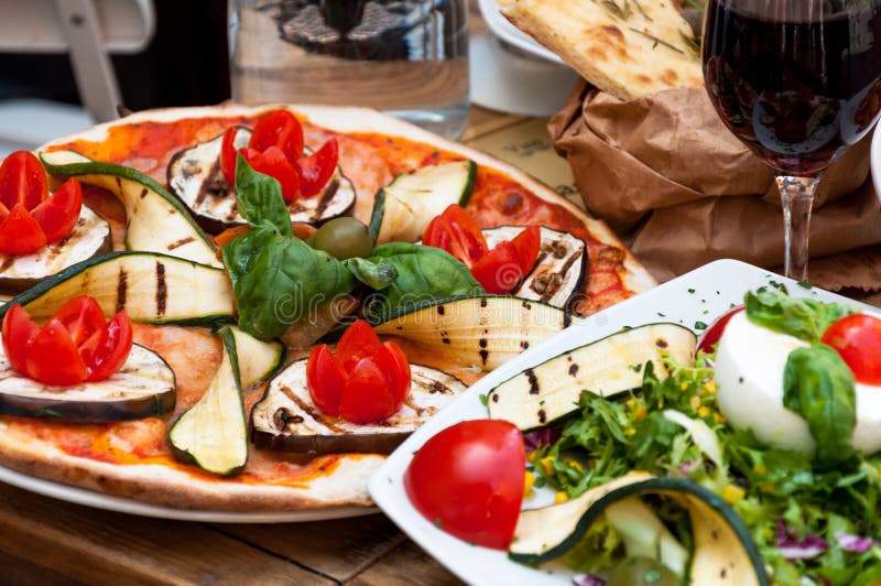 Served vegetarian meal at italian restaurant - vegetarian pizza with zucchini, eggplant, tomato and salad. Served vegetarian meal at italian restaurant - vegetarian pizza with zucchini, eggplant, tomato and salad