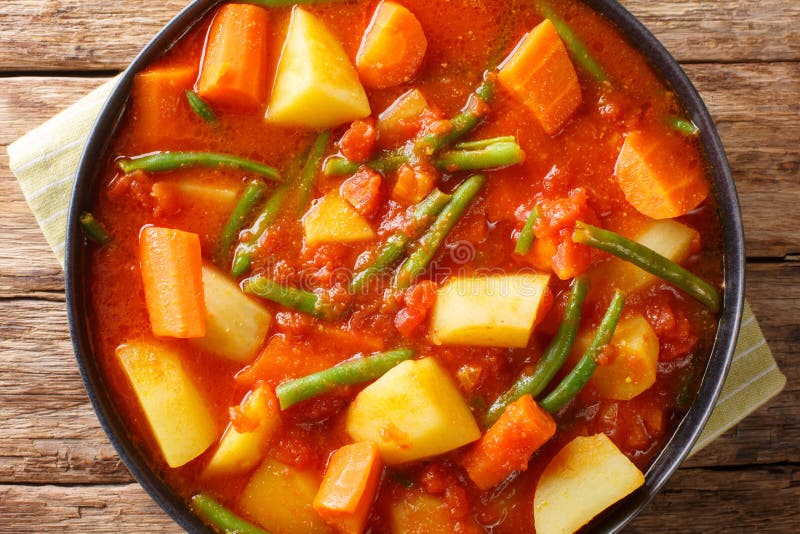 Vegetarian stew of carrots, green beans and potatoes in a spicy tomato sauce close-up in a bowl. Horizontal top view