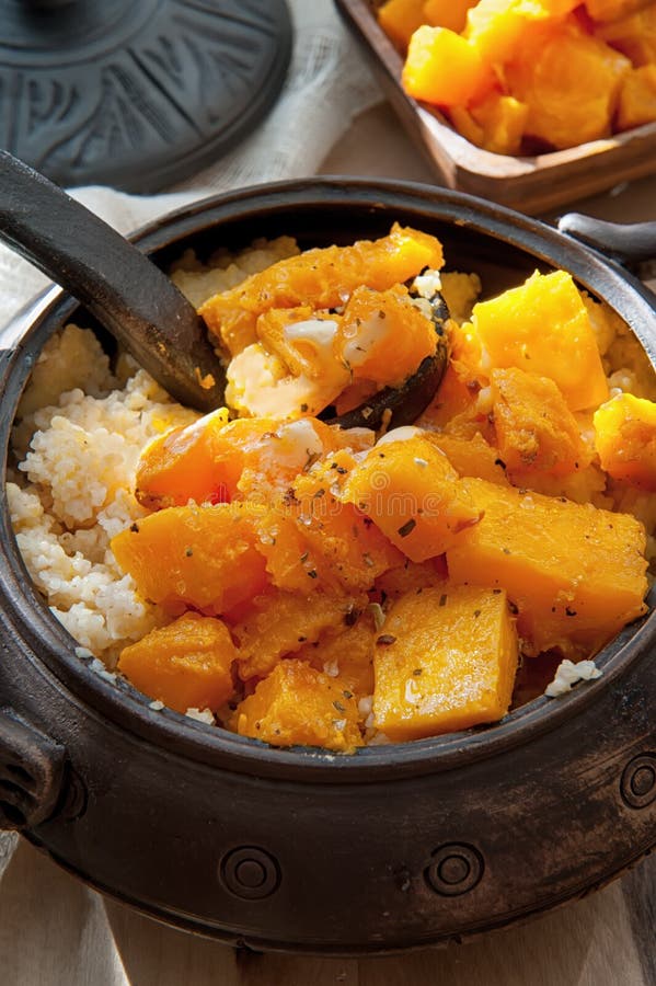 Vegetarian wheat porridge with large bright orange pieces of juicy fried pumpkin in a clay pot in a rustic style organic food royalty free stock photography Vegetarian wheat porridge with large bright orange pieces of juicy fried pumpkin in a clay pot in a rustic style organic food royalty free stock photography