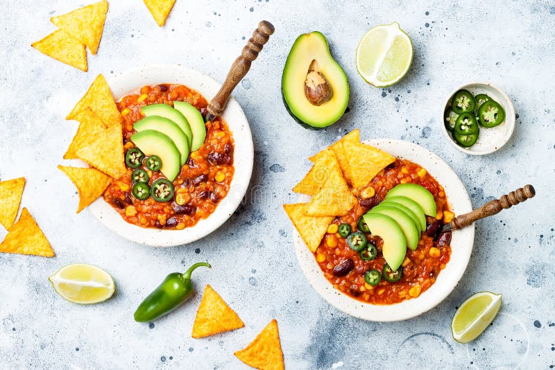 Vegetarian chili con carne with lentils, beans, nachos, lime, jalapeno. Mexican traditional dish. Vegetarian chili con carne with lentils, beans, nachos, lime, jalapeno. Mexican traditional dish