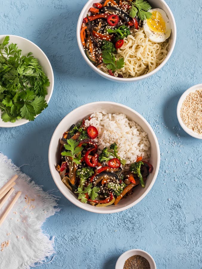 Vegetarische lunchlijst in de Aziatische stijl - de kommen met rijst, noedels, groente bewegen gebraden gerecht Op een blauwe ach stock fotografie Vegetarische lunchlijst in de Aziatische stijl - de kommen met rijst, noedels, groente bewegen gebraden gerecht Op een blauwe ach stock fotografie