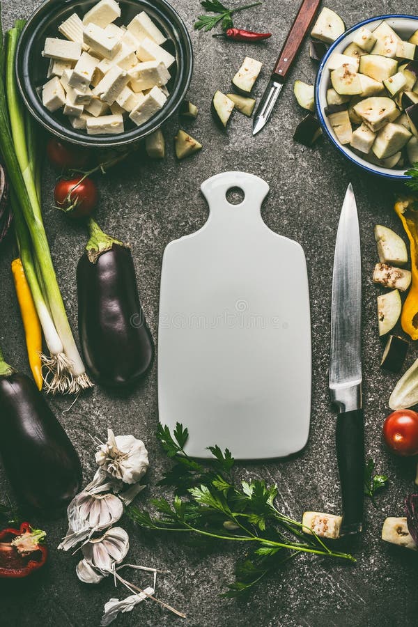 Vegetariska matingredienser med grönsaker, örter, fetaost, kryddor och kökkniven runt om skärbrädan, bästa sikt, ram royaltyfri foto Vegetariska matingredienser med grönsaker, örter, fetaost, kryddor och kökkniven runt om skärbrädan, bästa sikt, ram royaltyfri foto