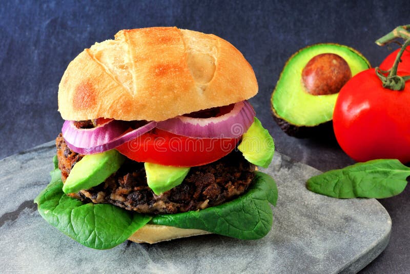 Veggie burger with avocado and spinach on a dark background