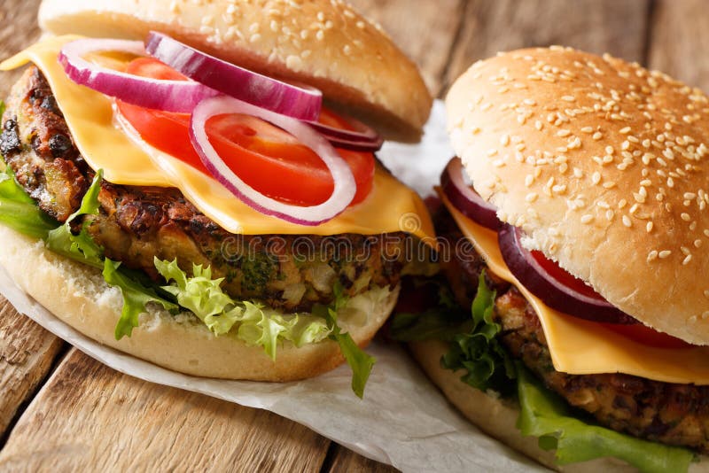 Veggie burger with fresh lettuce, onions, tomatoes and cheddar cheese close-up. horizontal