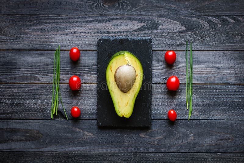 Veggie Food composition with half avocado over a darkdish stock photos
