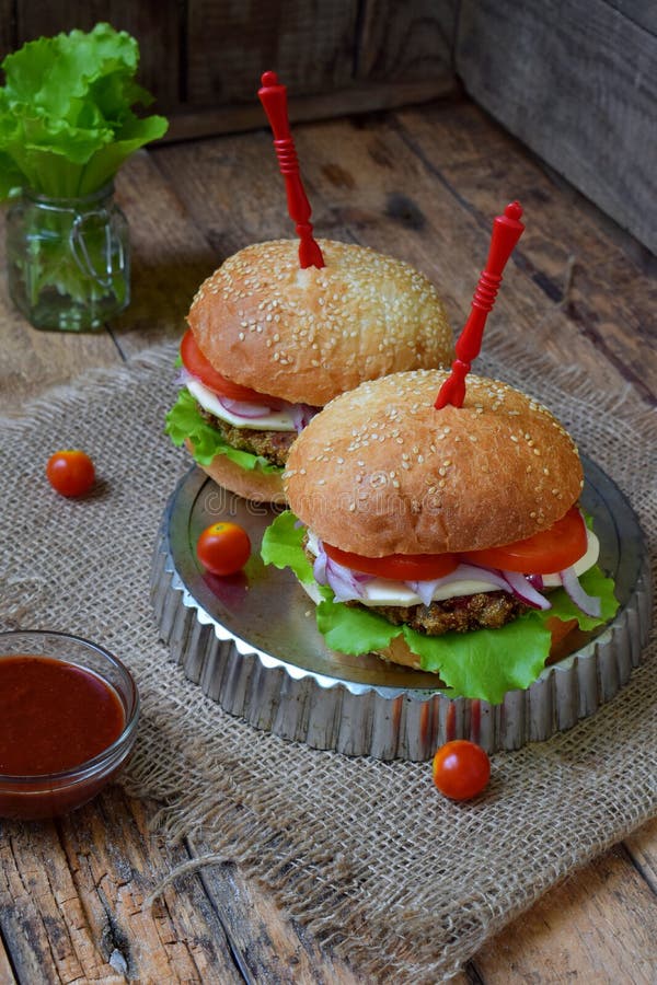 Veggiehamburgare med en kotlett av aubergine, grönsallat, inlagda lökar, tomat på en brun träbakgrund arkivfoto Veggiehamburgare med en kotlett av aubergine, grönsallat, inlagda lökar, tomat på en brun träbakgrund arkivfoto