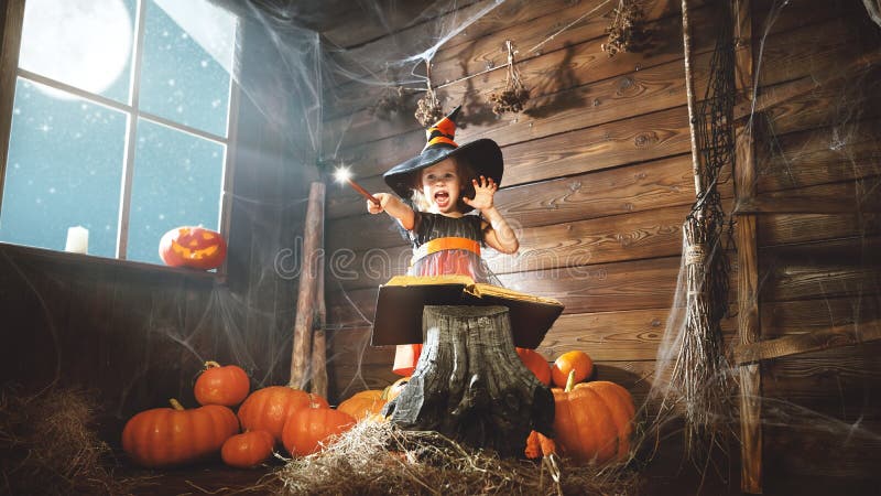 Veille de la toussaint petite sorcière d'enfant avec la baguette magique magique et lire un magnétique photos libres de droits Veille de la toussaint petite sorcière d'enfant avec la baguette magique magique et lire un magnétique photos libres de droits