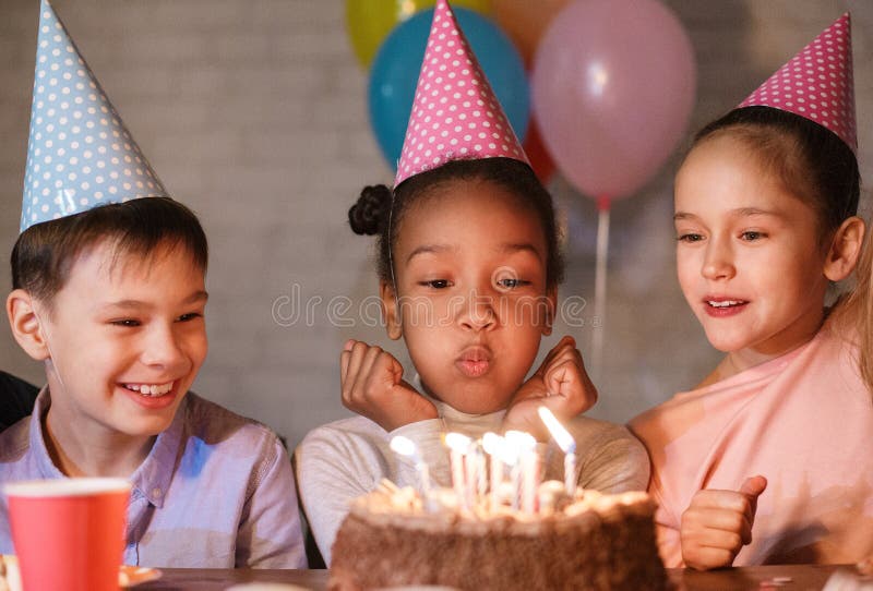 Velas de sopro da menina no bolo de aniversário, comemorando o aniversário imagens de stock royalty free Velas de sopro da menina no bolo de aniversário, comemorando o aniversário imagens de stock royalty free