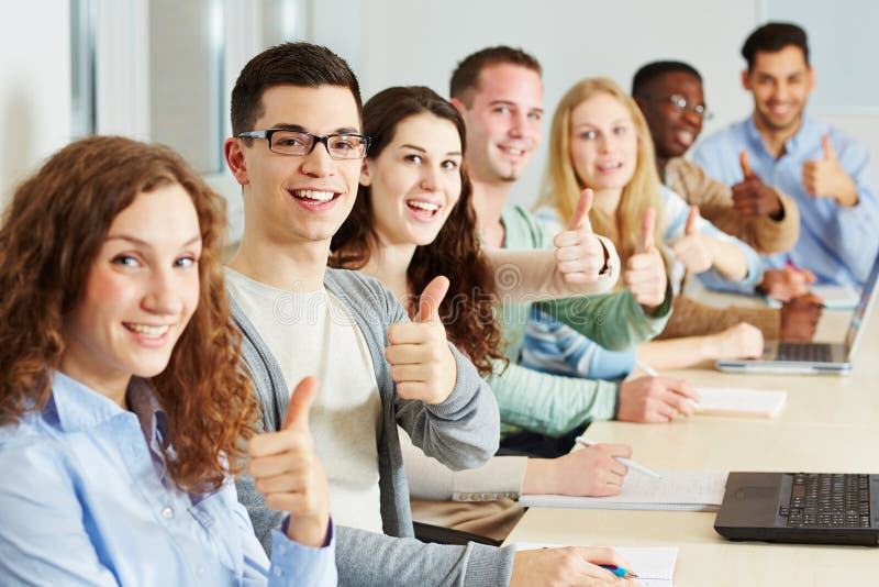 Many happy students holding their thumbs up in class. Many happy students holding their thumbs up in class