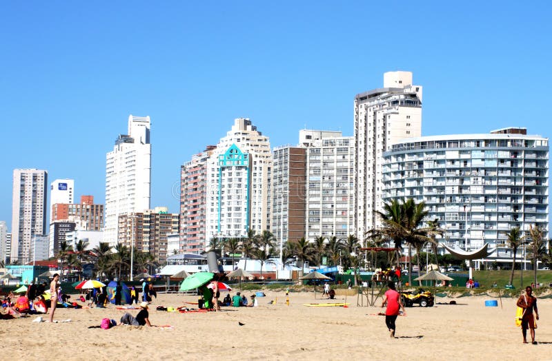 DURBAN, SOUTH AFRICA - MAY 3, 2014: Many people enjoy a sunny morning at North beach with City skyline in background in Durban South Africa. DURBAN, SOUTH AFRICA - MAY 3, 2014: Many people enjoy a sunny morning at North beach with City skyline in background in Durban South Africa