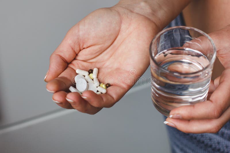 Vele pillen en drugs in vrouwenhand Zij houdt een glas water De arts adviseerde pillen royalty-vrije stock foto Vele pillen en drugs in vrouwenhand Zij houdt een glas water De arts adviseerde pillen royalty-vrije stock foto