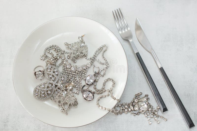 Velen fonkelende valse diamantjuwelen op een plaat met een mes en een vork Het concept het luxeleven, rijkdom, glamour royalty-vrije stock afbeelding Velen fonkelende valse diamantjuwelen op een plaat met een mes en een vork Het concept het luxeleven, rijkdom, glamour royalty-vrije stock afbeelding