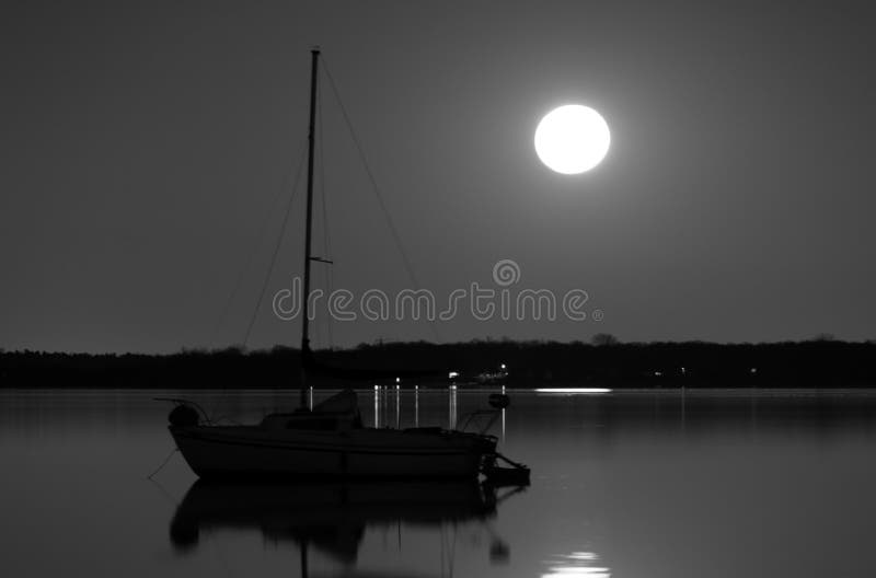 Velero debajo de una Luna Llena anclada en un espejo como el lago foto de archivo libre de regalías Velero debajo de una Luna Llena anclada en un espejo como el lago foto de archivo libre de regalías