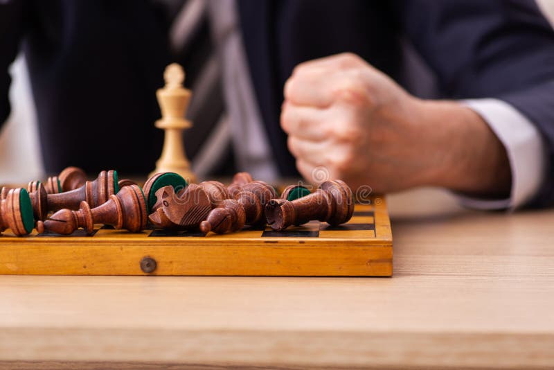 Mão de empresário movendo a figura do rei do xadrez de ouro durante a  competição do tabuleiro de xadrez.
