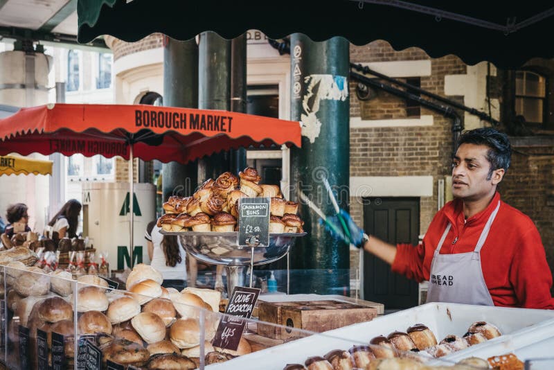 Vendedor en un soporte de la comida de la cabeza del pan en el mercado de la ciudad, Londres, Reino Unido imagenes de archivo Vendedor en un soporte de la comida de la cabeza del pan en el mercado de la ciudad, Londres, Reino Unido imagenes de archivo