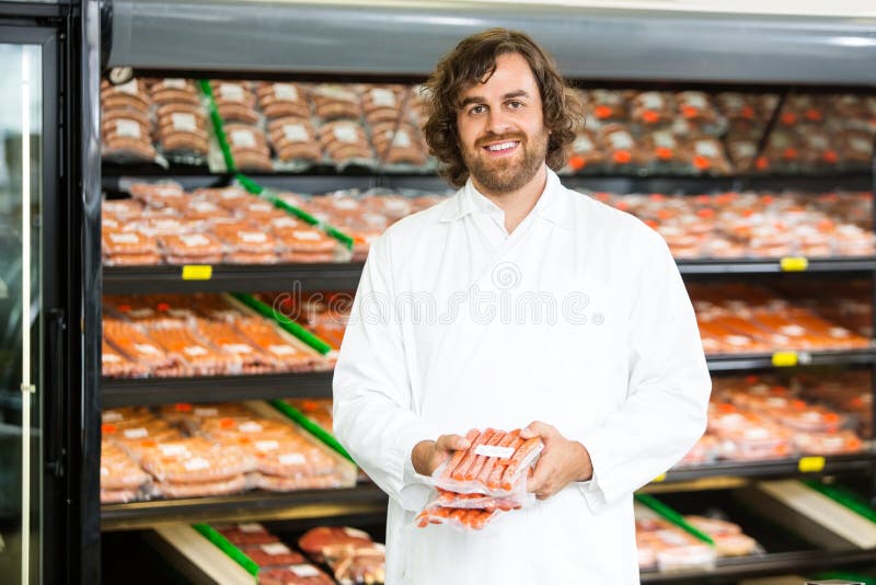 Vendedor feliz Holding Meat Packages no contador imagem de stock Vendedor feliz Holding Meat Packages no contador imagem de stock