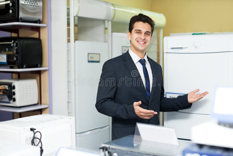 Vendedor masculino amigável na seção dos aparelhos eletrodomésticos imagens de stock royalty free Vendedor masculino amigável na seção dos aparelhos eletrodomésticos imagens de stock royalty free