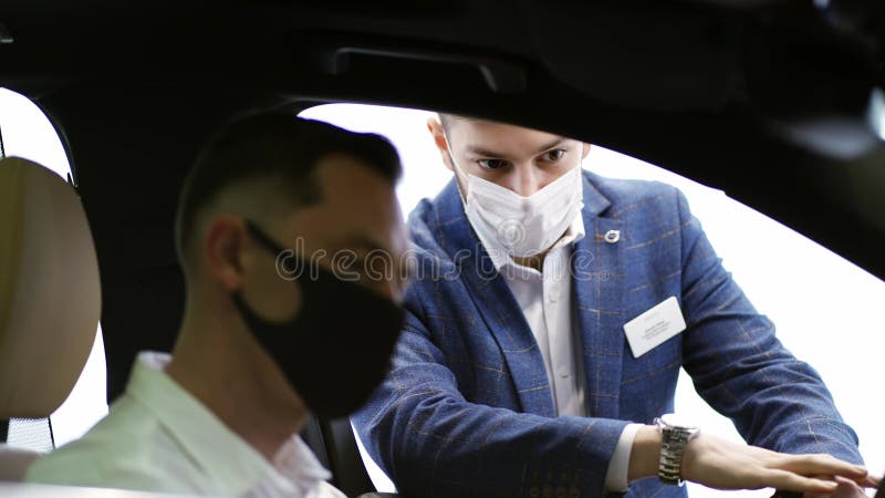 Vendedor presentando un coche de clase ejecutiva a un hombre dentro de la sala de espectáculos metrajes