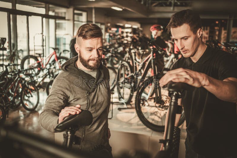 Vendedor que mostra uma bicicleta nova a cliente interessado na loja da bicicleta