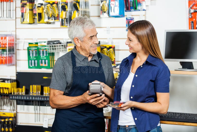 Vendeur Holding Electronic Reader tandis que client photos stock Vendeur Holding Electronic Reader tandis que client photos stock