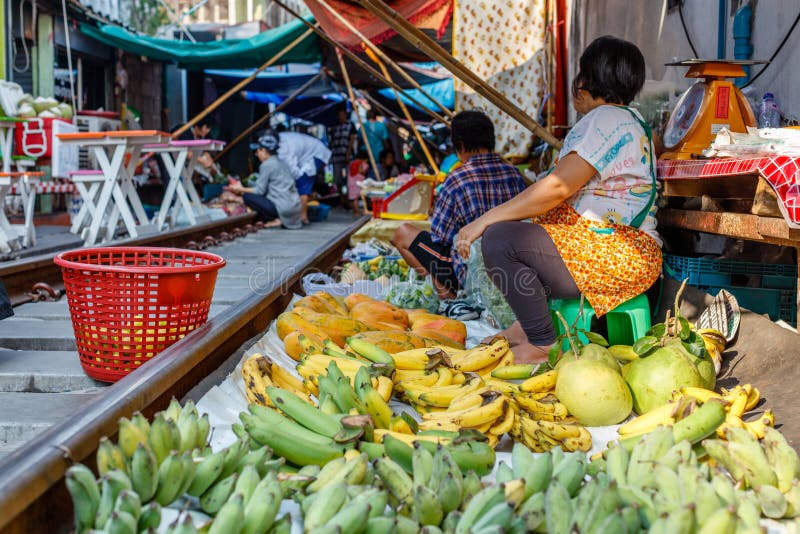 Vendeurs au marché ferroviaire célèbre de Maeklong vendant des fruits et légumes aux voies de chemin de fer, province de Samut So images stock Vendeurs au marché ferroviaire célèbre de Maeklong vendant des fruits et légumes aux voies de chemin de fer, province de Samut So images stock