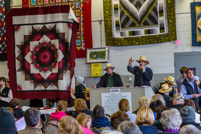 Bart, PA, USA - March 3, 2018: Amish auctioneers sell quilts at the annual Mud Sale at the Bart Fire Company. Bart, PA, USA - March 3, 2018: Amish auctioneers sell quilts at the annual Mud Sale at the Bart Fire Company.
