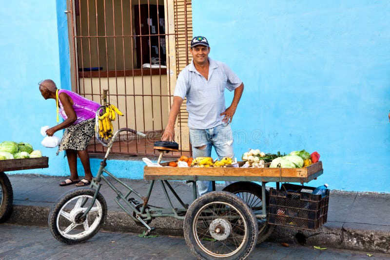 Camaguey, Cuba - December 19, 2016: Street vendor selling fruit and vegetables on his bike in the streets of Camaguey, Cuba. Camaguey, Cuba - December 19, 2016: Street vendor selling fruit and vegetables on his bike in the streets of Camaguey, Cuba
