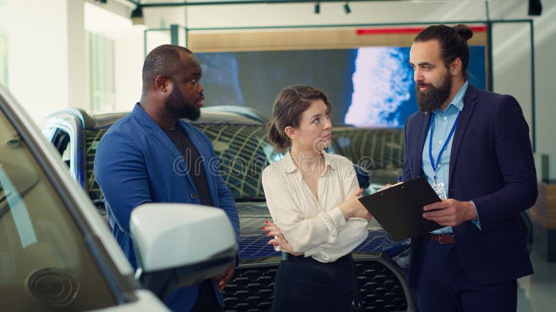 Venditore di auto che legge gli appunti ai clienti fornendo informazioni immagini stock libere da diritti