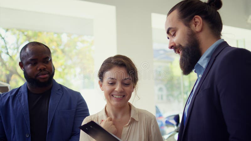 Venditore di autoveicoli che pone domande ai clienti immagine stock