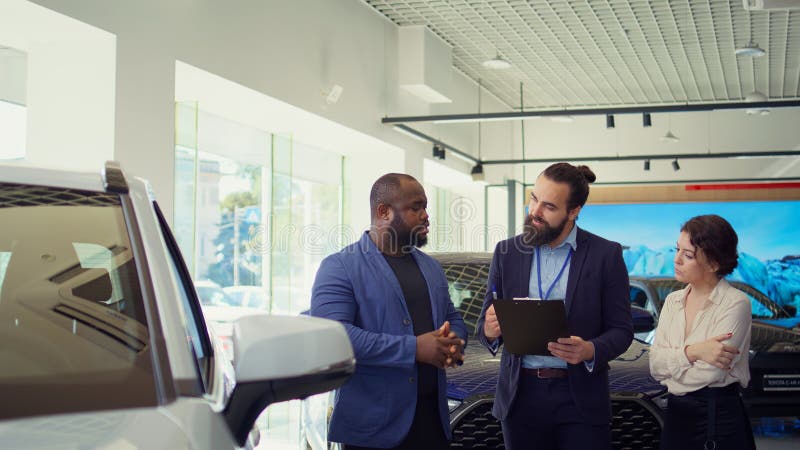 Venditore di concessionari rispondendo alle domande dei clienti sulle automobili fotografia stock libera da diritti