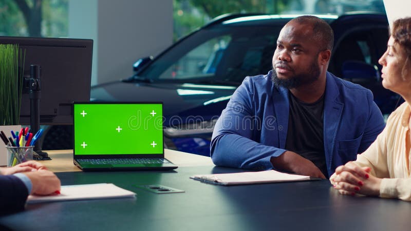 Venditore di conduzione che mostra modelli di auto su computer portatile per i clienti fotografia stock libera da diritti