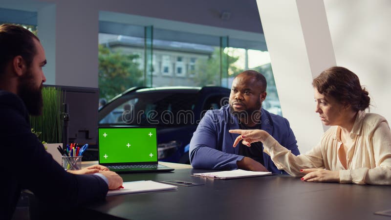 Venditore di conduzione che mostra modelli di auto su computer portatile per i clienti fotografie stock libere da diritti