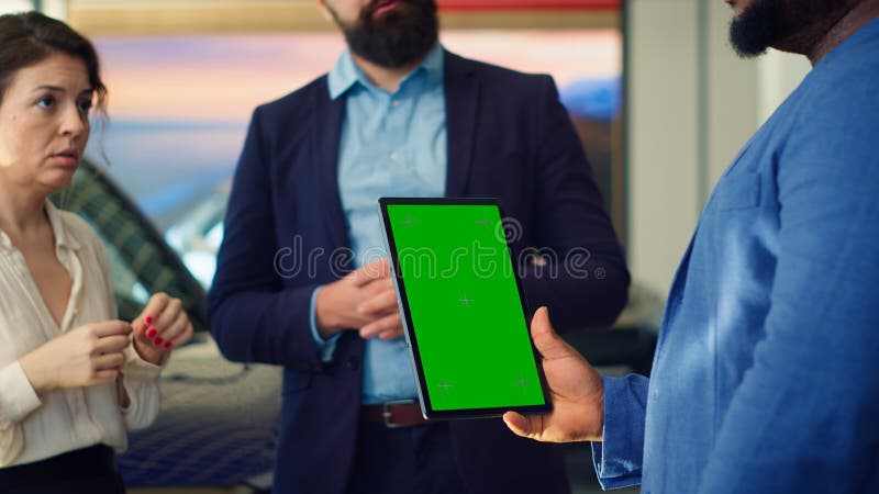 Venditore di conduzione che mostra modelli di auto sul tablet green screen per i clienti fotografia stock libera da diritti