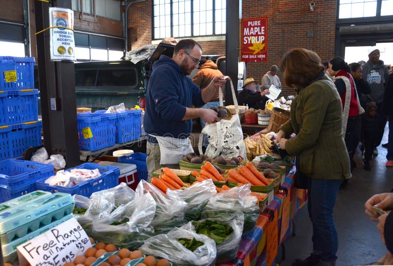 DETROIT, MI - FEBRUARY 6: A vendor bags produce for a customer at Eastern Market, the largest historic public market district in the United States, on February 6, 2016. DETROIT, MI - FEBRUARY 6: A vendor bags produce for a customer at Eastern Market, the largest historic public market district in the United States, on February 6, 2016.
