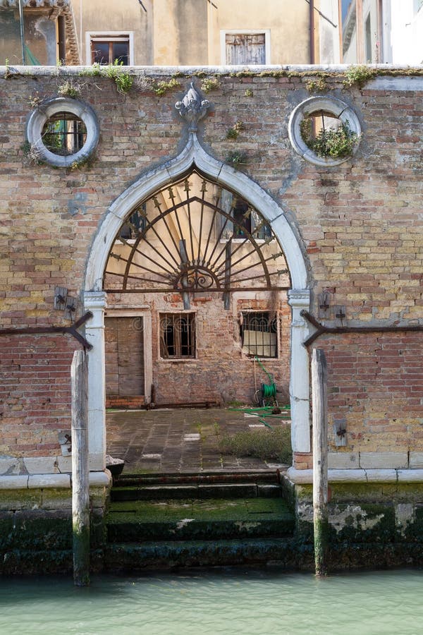 Venedig, Italien Alte gewölbte Wassertür weg von einem Kanal in einer verwitterten Backsteinmauer lizenzfreies stockbild