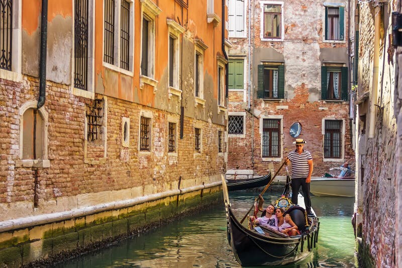 Venedig Italien - Augusti 22, 2018: Gondolen härskade vid en gondoljär i en smal gatakanal av Venedig royaltyfri bild Venedig Italien - Augusti 22, 2018: Gondolen härskade vid en gondoljär i en smal gatakanal av Venedig royaltyfri bild