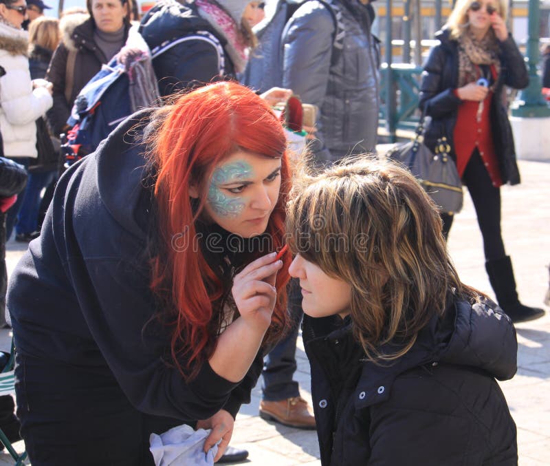 Editorial usefulness, a woman paints a tourist face outdoor at Venice carnival. Editorial usefulness, a woman paints a tourist face outdoor at Venice carnival