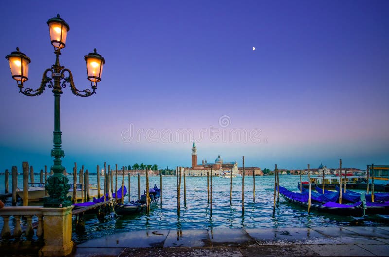 Venetië, straatlantaarn en gondels of gondole op zonsondergang en kerk op achtergrond. Italië
