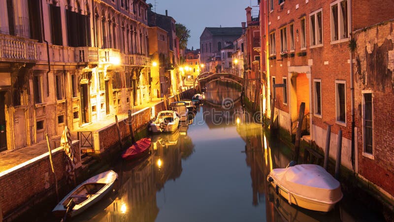 Venezia, Italia Barche al canale di notte in città Venezia cityscape Vecchia strada sull'isola di Venezia con illuminazione immagine stock libera da diritti Venezia, Italia Barche al canale di notte in città Venezia cityscape Vecchia strada sull'isola di Venezia con illuminazione immagine stock libera da diritti