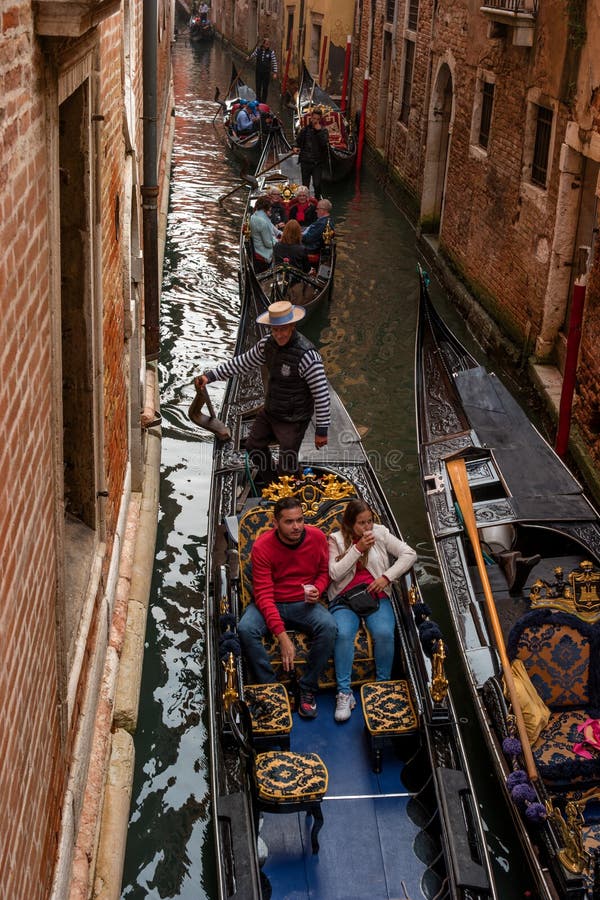 Venezia, Italia - 13 ottobre 2017: I turisti navigano su una gondola su un canale stretto La gondola pienamente è decorata con ro fotografia stock Venezia, Italia - 13 ottobre 2017: I turisti navigano su una gondola su un canale stretto La gondola pienamente è decorata con ro fotografia stock