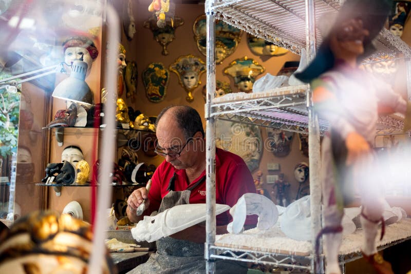 Venice, Italy - 2 february 2021: artisan making venice carnival masks at work in his shop. Venetian masks atelier and workshop