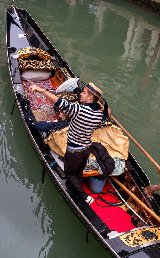 Venice, Italy - October 13, 2017. Tourists swim the gondola along a narrow canal. Gondolier points to attractions. The royalty free stock images Venice, Italy - October 13, 2017. Tourists swim the gondola along a narrow canal. Gondolier points to attractions. The royalty free stock images