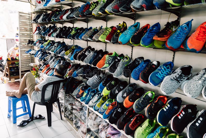 Venta Que Muchos De Zapatillas De Deporte Con El Vendedor Se Sientan En El Frente De Tienda Hanoi, Vietnam De La Ti Imagen archivo editorial - Imagen de